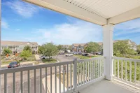Charming balcony view overlooking scenic residential community with lush greenery and pristine pathways on a sunny day.