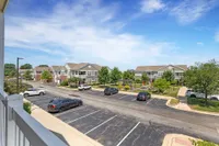 Beautiful suburban view showcasing modern townhouses, well-maintained greenery, and a spacious parking area under a vibrant blue sky.