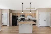 Modern kitchen with granite countertops, sleek pendant lighting, and elegant wooden cabinetry for a stylish, welcoming space.