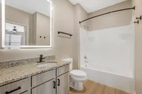 Modern bathroom with granite countertop, sleek fixtures, and a well-lit mirror enhancing elegance.