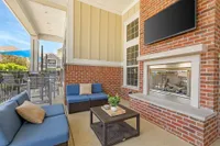 Charming outdoor lounge featuring cozy seating with blue cushions, a modern brick fireplace, and inviting patio ambiance.