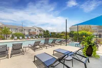 Inviting outdoor pool area with stylish lounge chairs and landscaped surroundings under a clear blue sky.