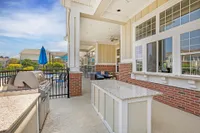 Charming outdoor patio with modern stainless steel grill, comfortable seating, and scenic views under a blue sky.