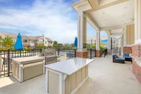 Inviting outdoor patio with a modern grill station, granite countertops, and cozy seating overlooking a scenic pool area.