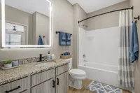 Modern bathroom featuring a sleek vanity with granite countertop, illuminated mirror, and stylish blue accents.