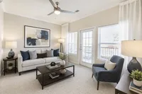 Bright and modern living room with elegant decor, featuring a cozy sofa, chic armchair, and vibrant artwork, complemented by large windows and natural light.