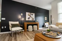 Modern apartment living room accent wall with lounge chair, wood console and contemporary artwork