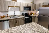 Newly renovated apartment kitchen with granite countertops, stainless steel appliances and wood-style cabinetry at Enclave at 127th