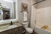 Newly renovated bathroom with spacious granite countertop, modern black hardware, and shower and bathtub combination.
