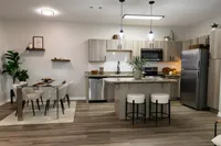 Open-concept renovated apartment home with kitchen island, dining area and stainless steel appliances at Enclave at 127th.