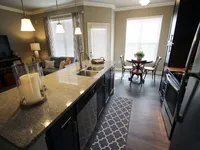 View of kitchen with stone counters, looking through to the dining area.