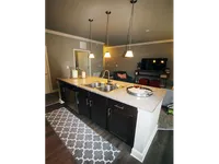View from kitchen overlooking stone counters and a breakfast bar, into the living room.
