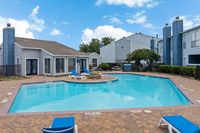 Charming apartment complex featuring a tranquil swimming pool, sun loungers, and cozy blue exterior, perfect for relaxation and leisure.
