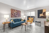 Modern living room with a stylish blue sofa, vibrant yellow armchair, and sleek tiled flooring, enhanced by elegant artwork and abundant natural light.