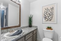 Elegant bathroom featuring a granite countertop, stylish framed mirror, and vibrant indoor plant decor.