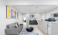 Modern office space featuring a stylish gray sofa, abstract wall art, and a cozy ambiance with natural light.