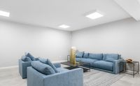 Modern living room with stylish blue couches, sleek decor, and soft gray walls offering a serene ambiance.