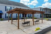 Charming outdoor patio with wooden pergola and modern seating, offering a relaxing communal space in a well-kept apartment complex.
