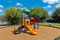 Vibrant playground featuring colorful slides and climbing structures surrounded by lush greenery, ideal for family fun.
