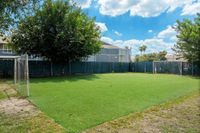Inviting outdoor soccer field with lush green turf, surrounded by mature trees, perfect for recreational play under a bright blue sky.