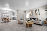 Modern living room with elegant decor, featuring cozy seating, abstract artwork, and a stylish dining area leading to a sleek kitchen.