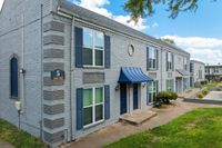 Charming apartment building with modern brick facade, large windows, and inviting blue accents, nestled in a serene green setting.