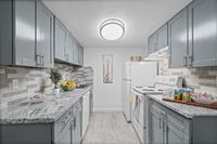 Modern kitchen with sleek gray cabinets, elegant granite countertops, stylish backsplash, and ambient lighting creating a sophisticated ambiance.