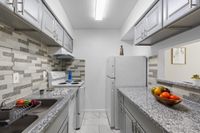 Modern kitchen with sleek granite countertops, stylish cabinetry, and bright tile backsplash.