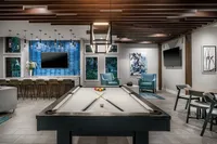 Clubroom with pool table, wall mounted tv and chairs.