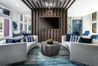 Club room with two grey couches, center table, modern rug and mounted tv