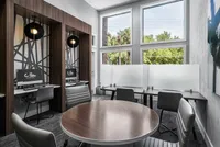 Study/work room with table, computers, and work desks next to window