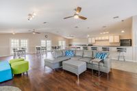 Community clubhouse with couch seating, dining style seating, and a kitchen area in the background.