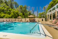 Rectangular community pool with lounge chairs and trees in background.