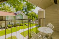 Bedroom balcony overlooking the community. There is a sidewalk surrounded by green space that leads to each apartment entrance.