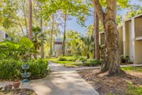 Outside view of the community buildings. There is a sidewalk that leads you throughout the community. There are trees and plants on both sides of the sidewalks.