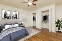Bedroom with hardwood floors, closet with door doors, wall art, plant, and blue bedding.