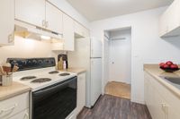 Kitchen with hardwood floors, beige cabinets, and white appliances.