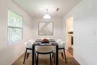 Dining area with white and black dining set, modern wall art and entrance to the kitchen to the right.