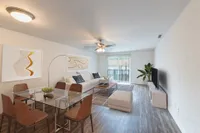 Living and Dining area with hardwood floors, beige walls, glass table, leather chairs, and a white couch.