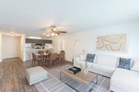 Living and Dining area with hardwood floors, beige walls, glass table, leather chairs, and a white couch.