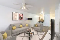 Close up of living room area with three couches, wall art, circular glass coffee table. You can see the kitchen and passthrough in the background to the right.