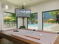 Billiard table with large windows and tv in background.