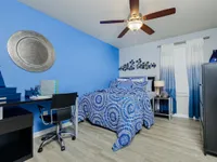 Bedroom with blue accent wall, ceiling fan, wood style floor and furniture.