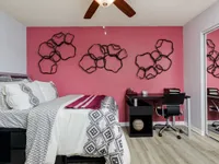 Bedroom with ceiling fan and furniture with red accent wall.