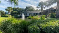 Lush landscaping with pond and fountain, and leasing office in background.