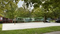 Sand volleyball court with trees in background.