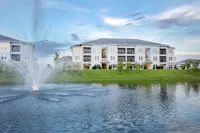 Apartment building exterior with lake and fountain in foreground.