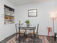 Dining area with hardwood floors, built in wall bar, standing lamp, and wall decor.