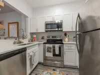 Kitchen with quartz countertops, hardwood floors, white cabinets, stainless steel appliances, and a passthrough