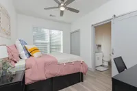 Living room with hardwood floors, desk with chair, ceiling fan, access to bathroom, and access to the main living area.